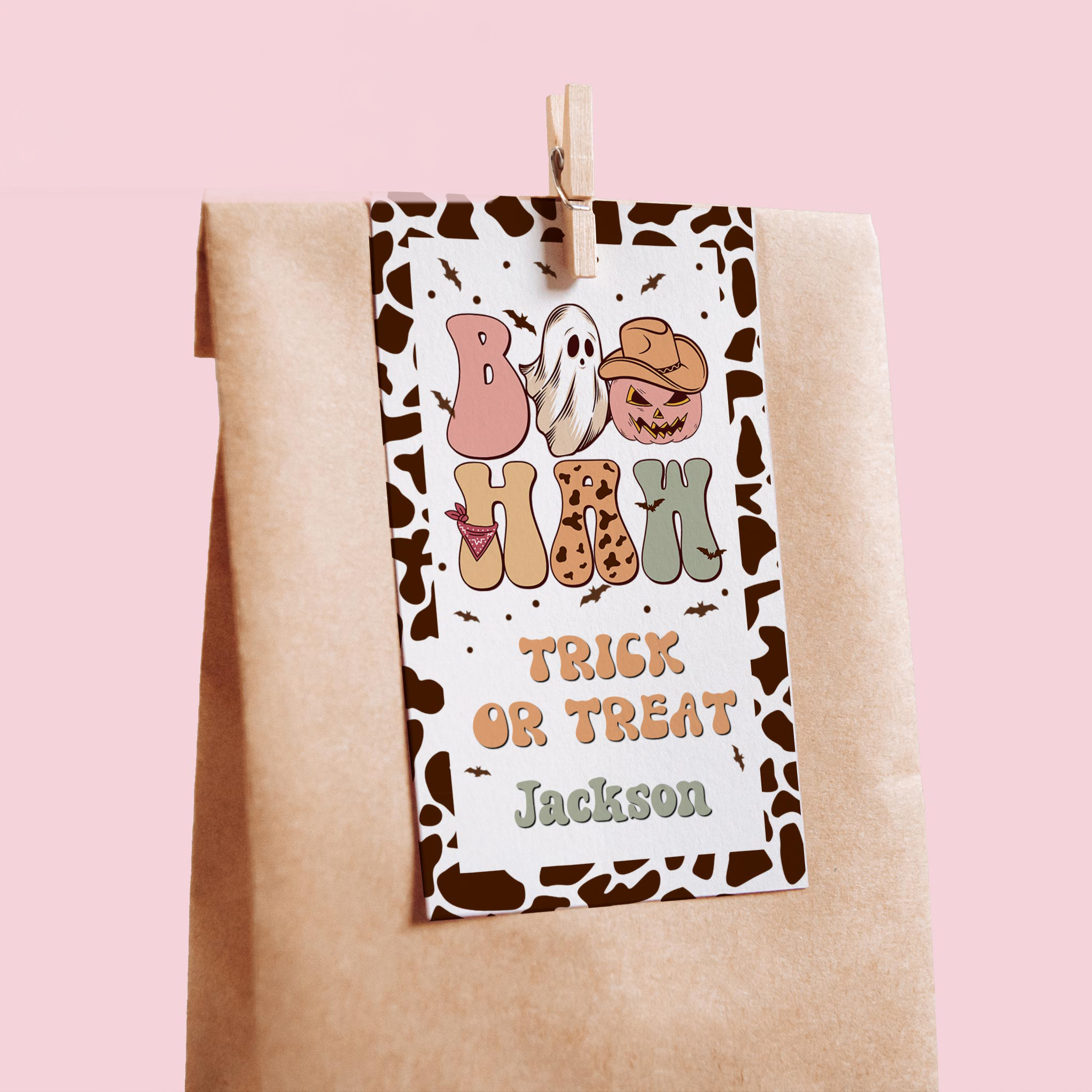 Halloween-themed tag with cartoon characters and text on a brown paper bag against a pink background