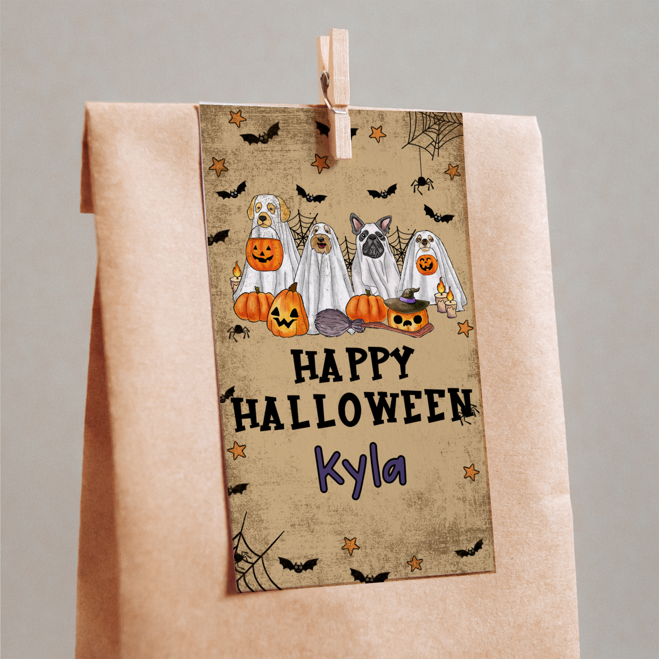 Halloween-themed towel with cartoon dogs dressed as ghosts and pumpkins, hanging on a wooden peg against a gray background.