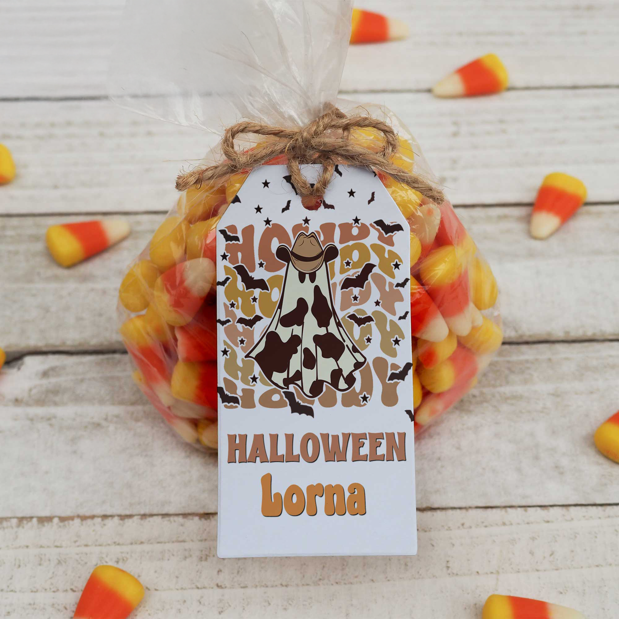 Halloween candy bag with a cowboy-themed tag on a wooden surface with candy corn.