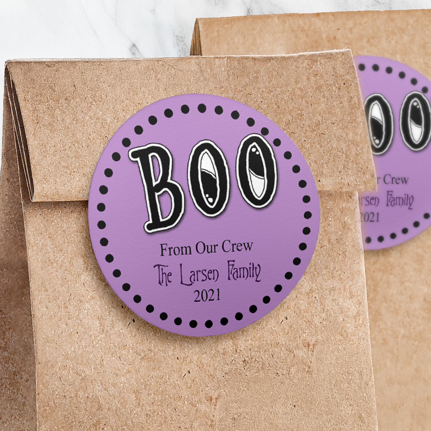 Round light purple sticker with black BOO on paper trick or treat bag