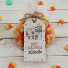 Halloween-themed candy bag with 'The Boo Crew' tag on a wooden surface with candy corn.