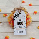 Halloween-themed candy bag with a personalized tag on a wooden surface.