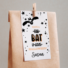 Halloween-themed gift bag with a decorative tag featuring a bat and text.